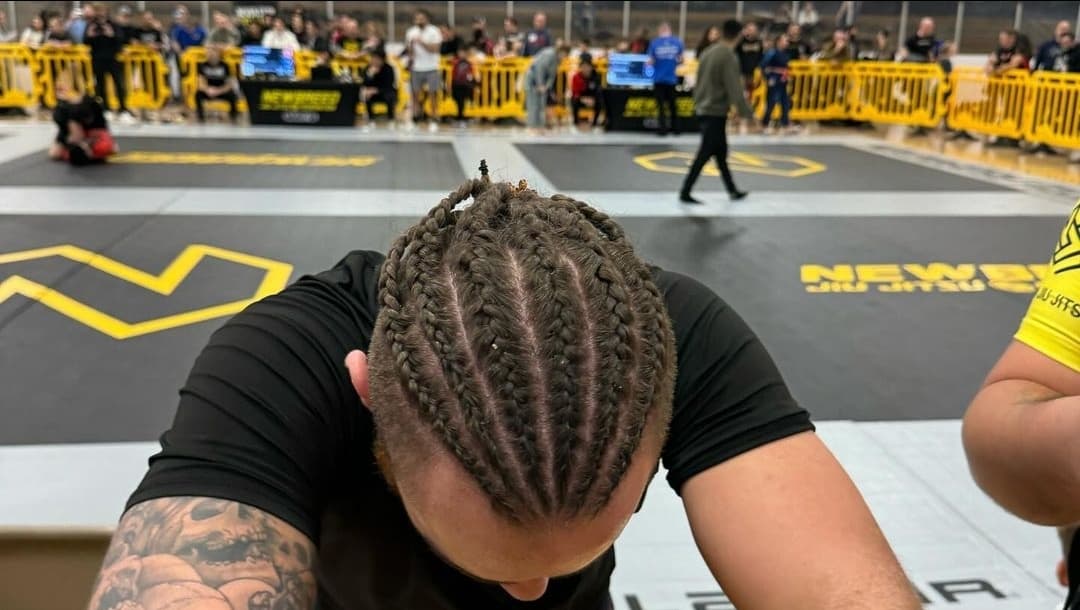 The author at a Newbreed jiu-jitsu tournament, head bowed, cornrows visible.